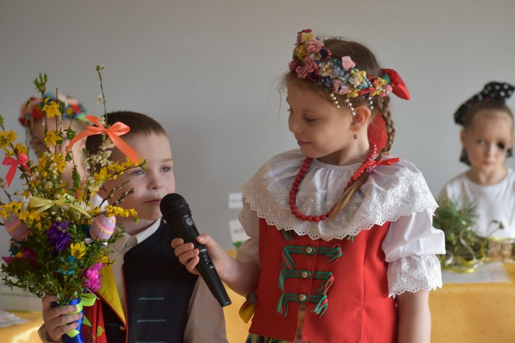 Dzieci stoją na środku i opowiadają o swojej palmie  